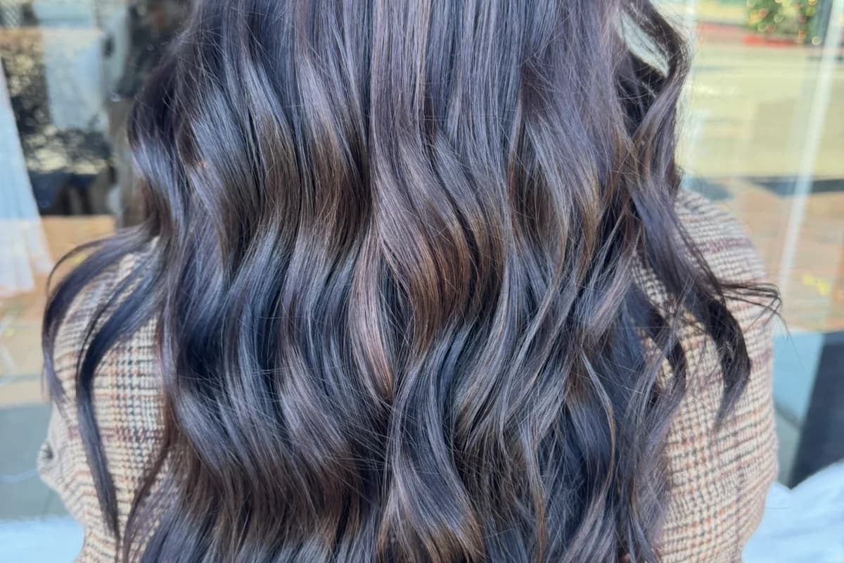 Dark mocha balayage with cool tones and dramatic dimension on long wavy hair by Brooke Holland